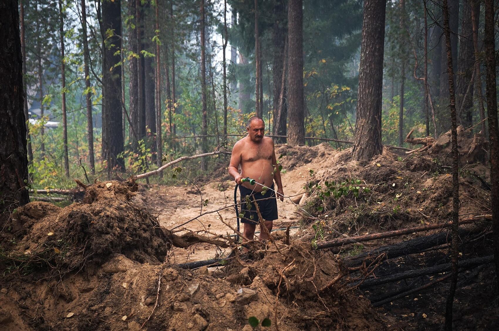 Садовод Сергей поливает торф за минеральной полосой. Фото: Арина Томашова / It's My City